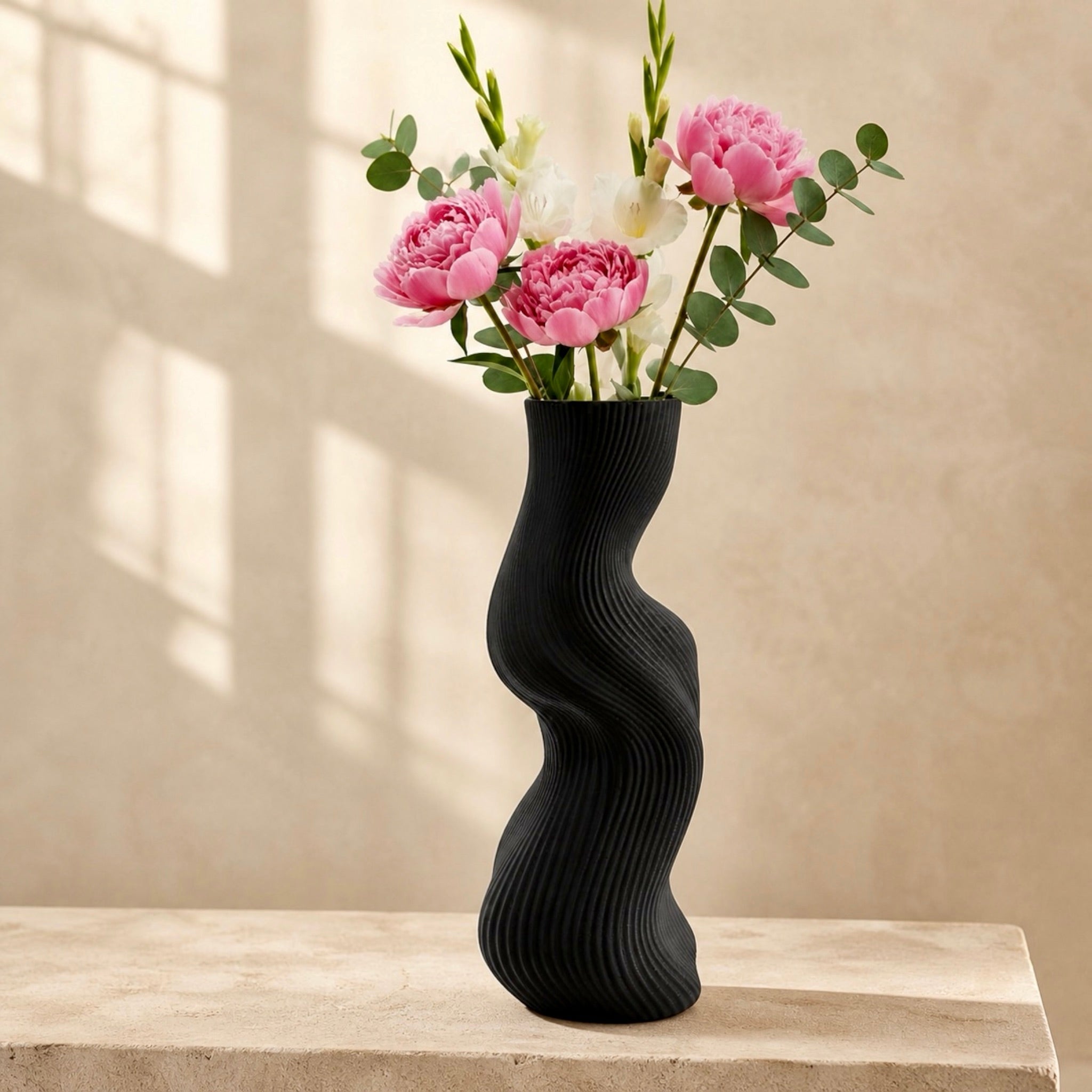 Black Uzoo Tanasul Vase styled on tall stand – sculptural wave centerpiece